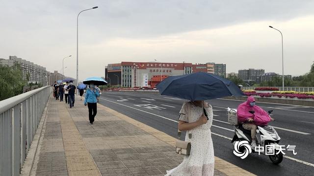 阵雨遇上北京早高峰 市民打伞出行