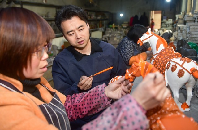 张毅鹏正在指导工人对唐三彩半成品上釉。黄政伟摄